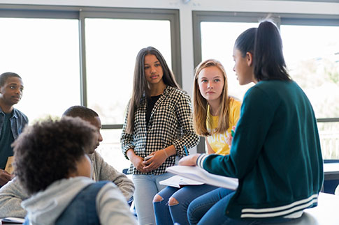 A group of six teenagers gather together and are having a discussion.