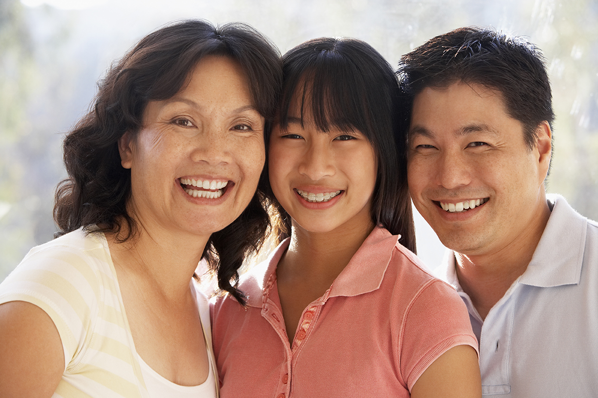 A family including an older woman, teenage girl, and adult man smile at the camera.