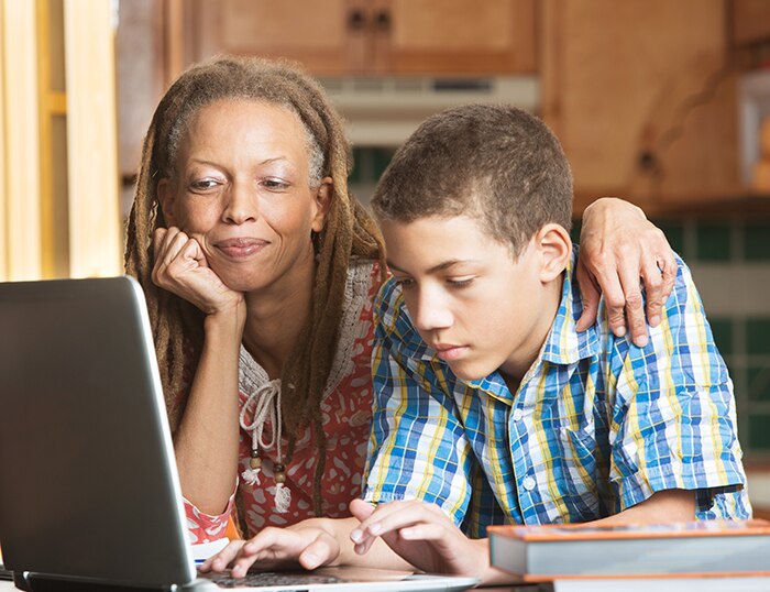 Una niña y su madre miran un computadora portátil