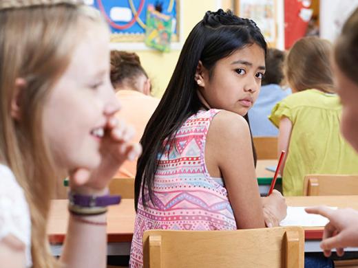 Niña mira como otras niñas hacen chismes sobre ella