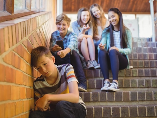 Child looks sad as others smile behind him