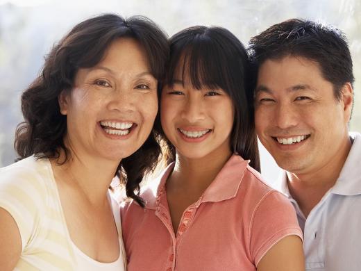 A family including an older woman, teenage girl, and adult man smile at the camera.